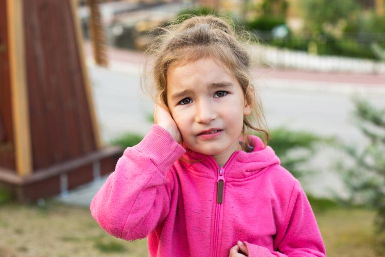 a young girl in pain from a childhood ear infection